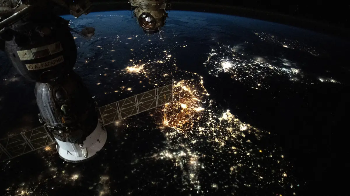 City lights of Europe at night, photographed from the International Space Station with a docked Soyuz spacecraft and solar panel in the foreground