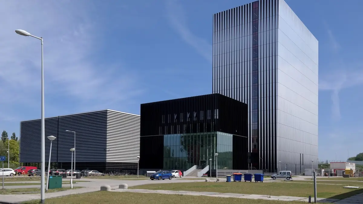 The Equinix AM3 and AM4 data centres in Amsterdam: a low black box with horizontal louvres and a tall mirrored tower under a blue sky.