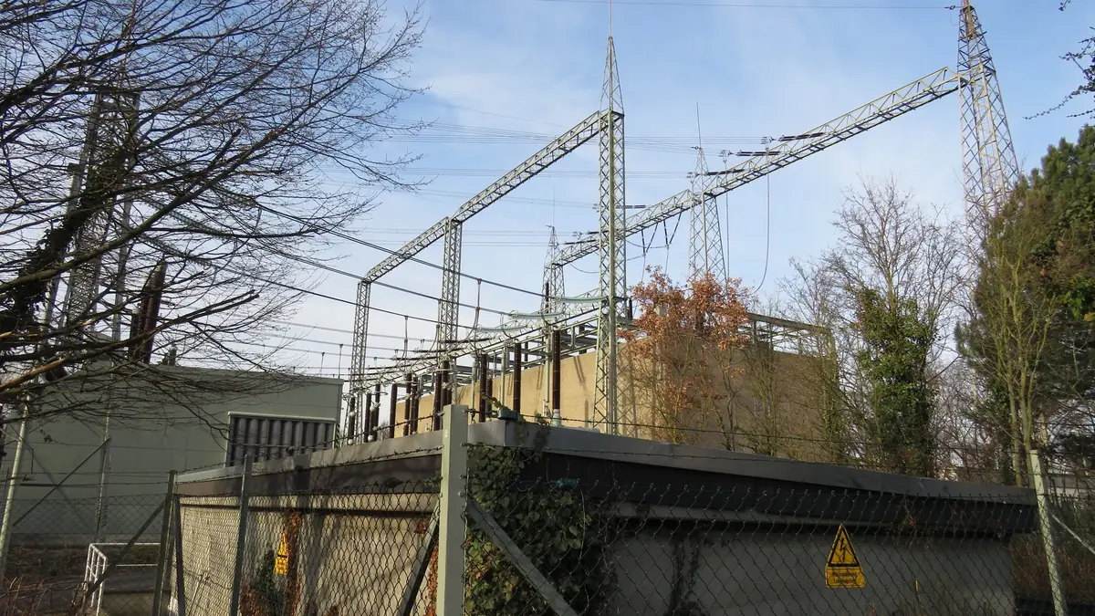 The 380/110 kV Frankfurt-Südwest substation in Frankfurt-Griesheim: lattice gantries and overhead lines above a fenced switchyard under a blue winter sky.