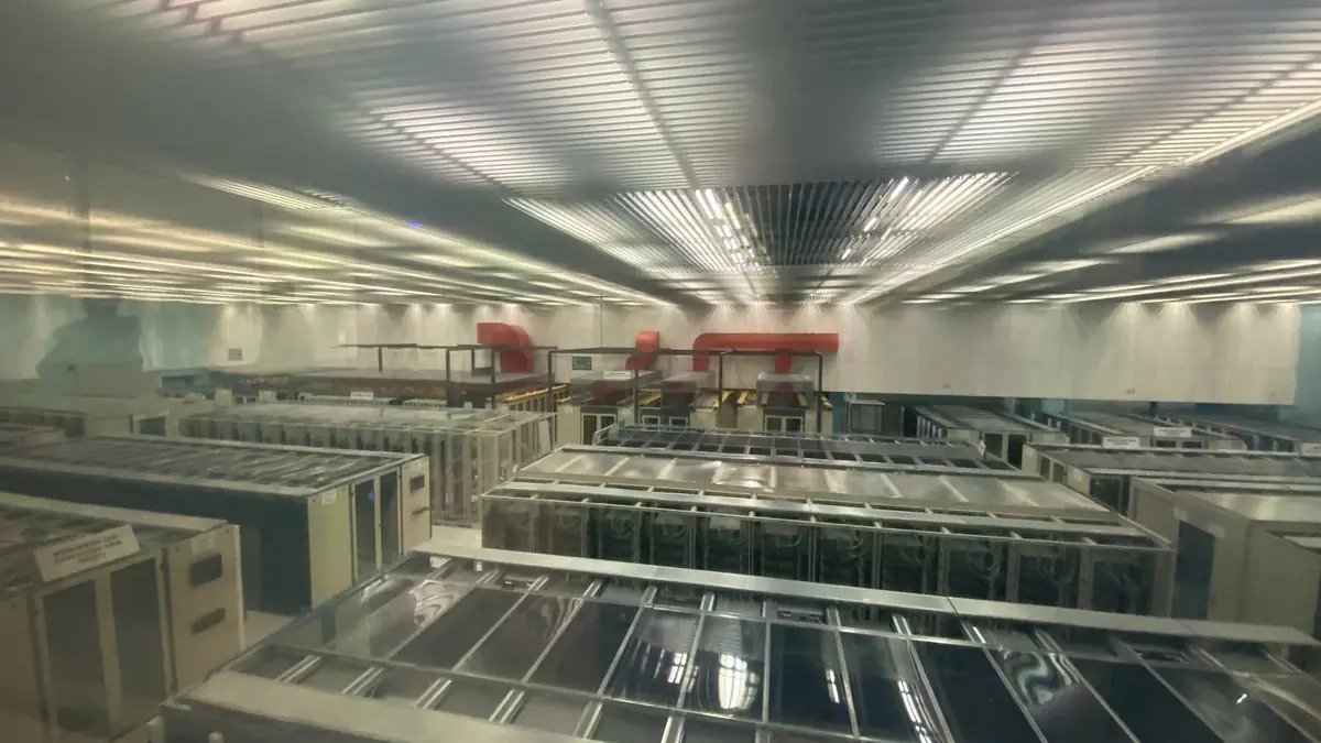 Rows of server and storage racks in the CERN data centre in Geneva, seen through a viewing window.